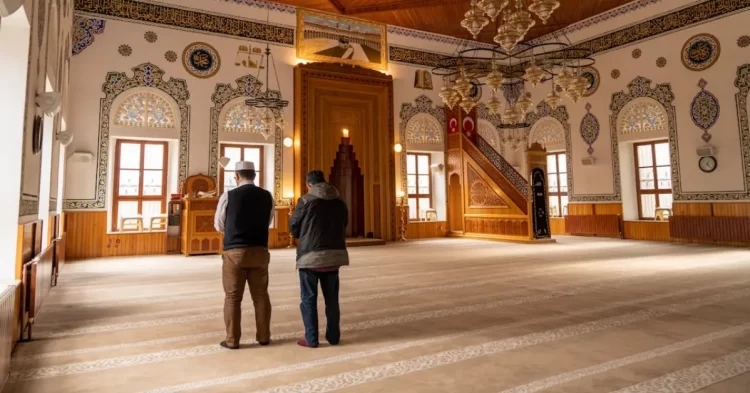 dua orang sedang melaksanakan shalat berjamaah di masjid