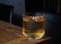 Segelas minuman beralkohol di atas meja kayu, ilustrasi hukum khamr dalam Islam