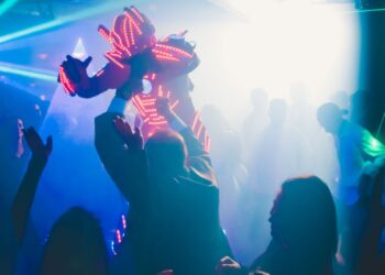 Siluet orang-orang menari di klub malam dengan lampu neon, ilustrasi hukum dugem dan nyawer dalam Islam