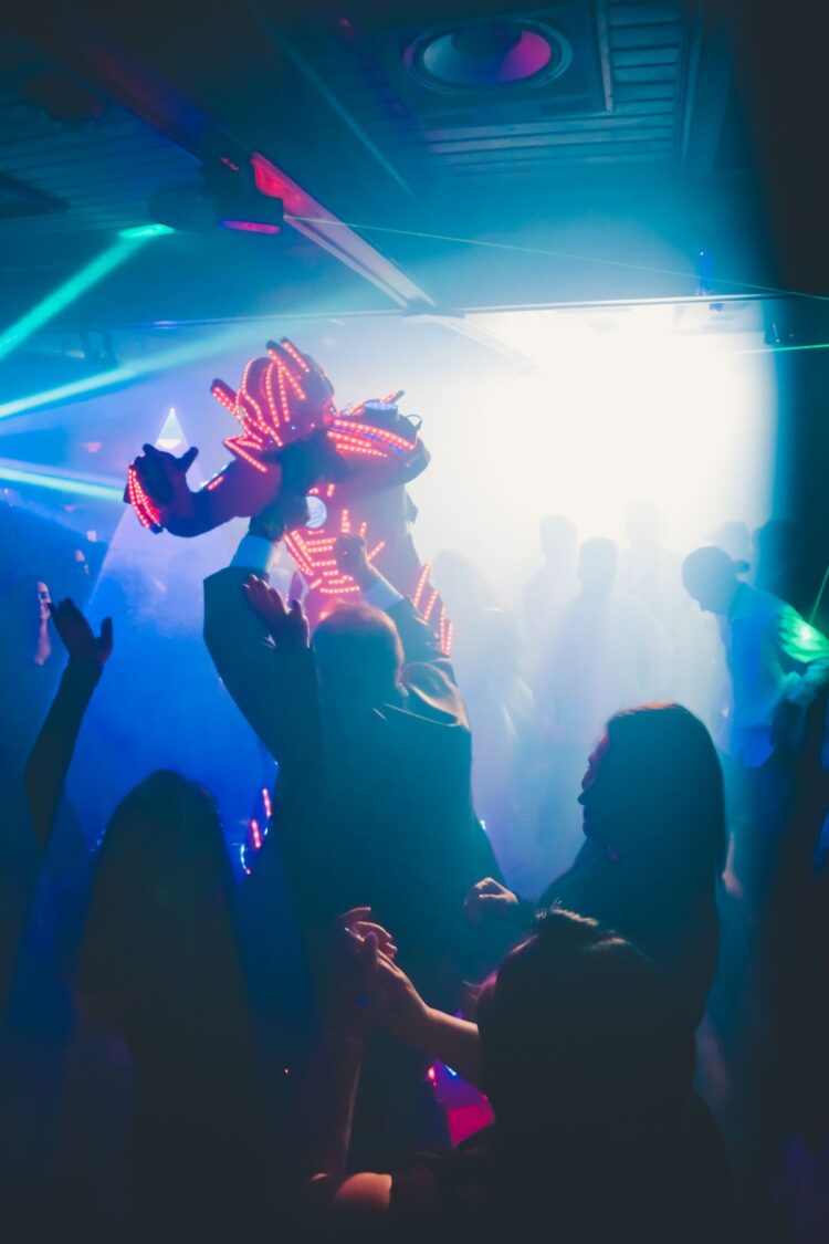 Siluet orang-orang menari di klub malam dengan lampu neon, ilustrasi hukum dugem dan nyawer dalam Islam
