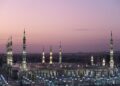 Pemandangan Masjid Nabawi di Madinah saat senja dengan menara menyala, ilustrasi hadits tentang 10 sahabat yang dijamin masuk surga