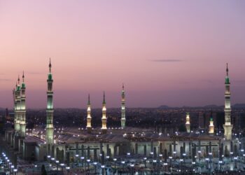 Pemandangan Masjid Nabawi di Madinah saat senja dengan menara menyala, ilustrasi hadits tentang 10 sahabat yang dijamin masuk surga