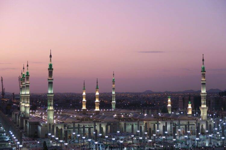 Pemandangan Masjid Nabawi di Madinah saat senja dengan menara menyala, ilustrasi hadits tentang 10 sahabat yang dijamin masuk surga