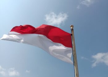 Bendera merah putih Indonesia berkibar di langit biru, ilustrasi klarifikasi hadits hubbul wathan minal iman