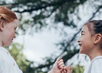 Dua anak perempuan melakukan pinky promise sambil tersenyum, ilustrasi hadits tentang kejujuran dan menepati janji