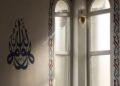 Interior masjid dengan kaligrafi Arab dan cahaya matahari dari jendela lengkung, ilustrasi hukum merayakan Maulid Nabi
