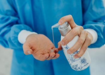 Tenaga medis menuangkan hand sanitizer ke tangan, ilustrasi hadits tentang wabah penyakit (tha'un) dan prinsip karantina