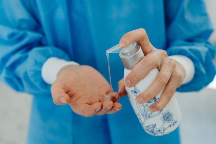 Tenaga medis menuangkan hand sanitizer ke tangan, ilustrasi hadits tentang wabah penyakit (tha'un) dan prinsip karantina