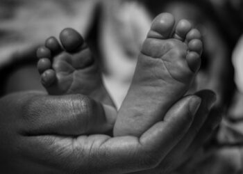Kaki bayi mungil digenggam lembut oleh tangan orang dewasa