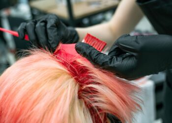 Tangan penata rambut mengoleskan pewarna pada rambut