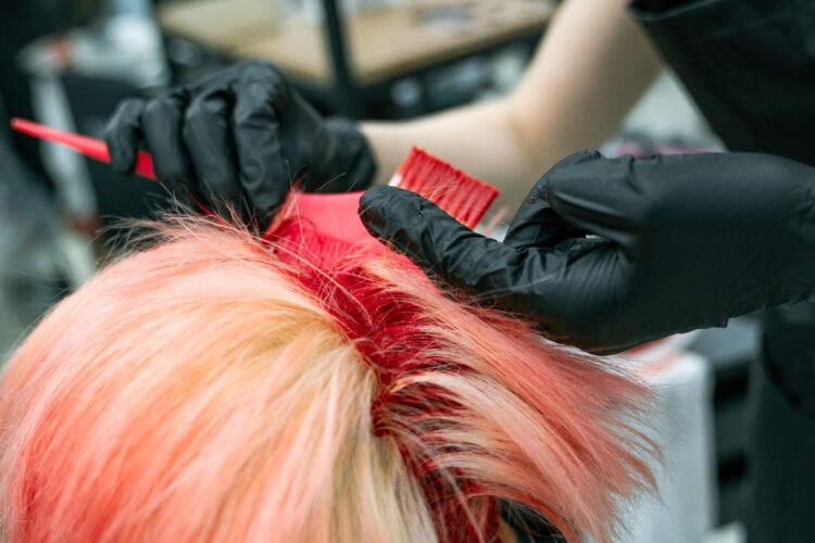Tangan penata rambut mengoleskan pewarna pada rambut