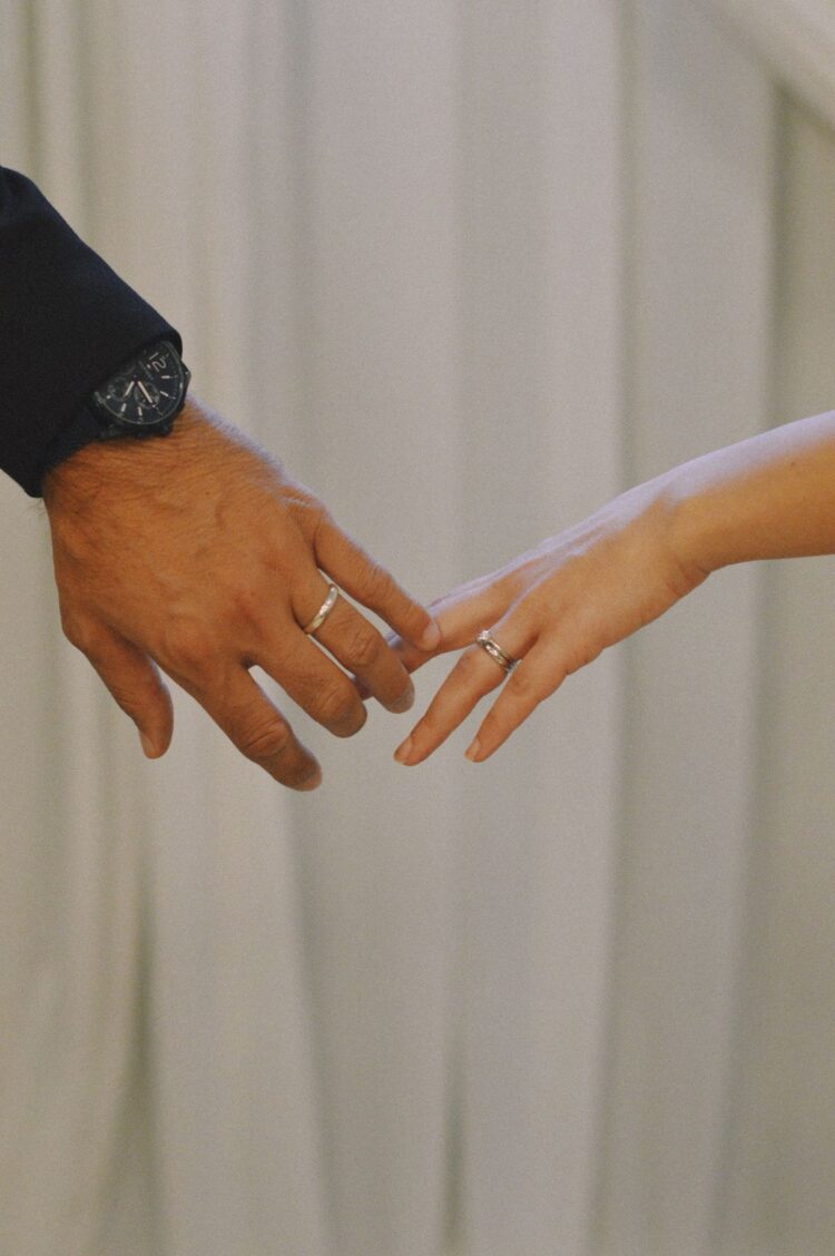 Tangan pasangan suami istri bergandengan dengan cincin nikah