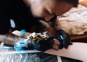 Seniman tato sedang membuat tato menggunakan mesin tato