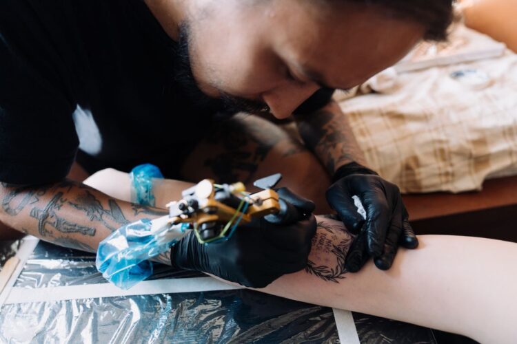 Seniman tato sedang membuat tato menggunakan mesin tato