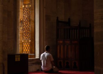 Seorang pria duduk sendirian beribadah di dalam masjid, ilustrasi hukum i'tikaf dalam Islam