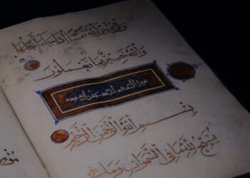Mushaf Al-Qur'an kuno terbuka dengan kaligrafi berhiaskan emas di latar gelap, ilustrasi keutamaan 2 ayat terakhir Surat Al-Baqarah