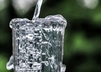 Air jernih dituangkan ke dalam gelas kaca, ilustrasi keutamaan air zamzam yang penuh berkah