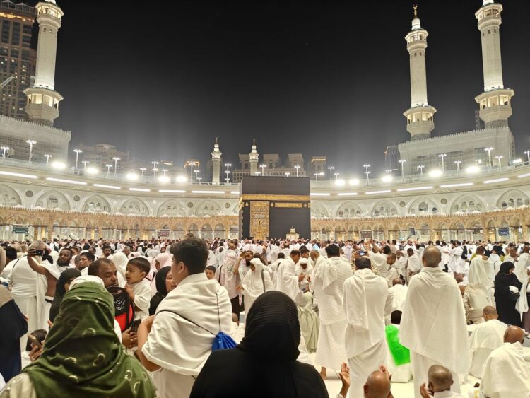 Jamaah berkumpul mengelilingi Kakbah di Masjidil Haram pada malam hari, ilustrasi keutamaan Surat Al-Fath