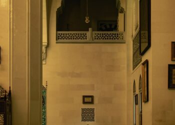 Seorang pria shalat sendirian di dalam masjid besar, ilustrasi keutamaan Surat Al-Fatihah sebagai induk Al-Qur'an