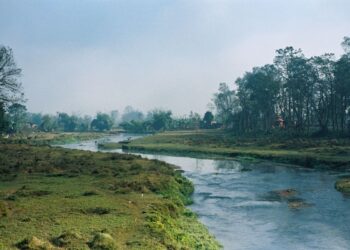 Sungai yang mengalir tenang di tengah padang hijau, ilustrasi keutamaan Surat Al-Kautsar dan telaga di akhirat