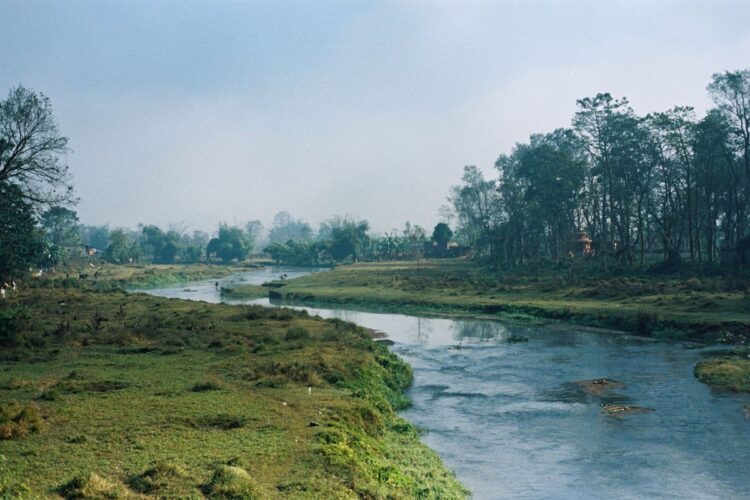 Sungai yang mengalir tenang di tengah padang hijau, ilustrasi keutamaan Surat Al-Kautsar dan telaga di akhirat