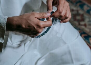 Tangan memegang tasbih mengenakan pakaian putih, ilustrasi keutamaan dzikir pagi dan petang Al-Ma'tsurat