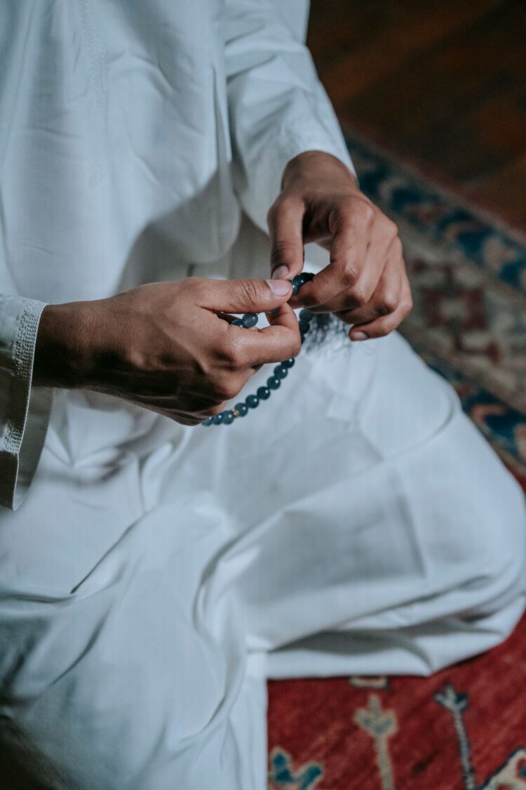 Tangan memegang tasbih mengenakan pakaian putih, ilustrasi keutamaan dzikir pagi dan petang Al-Ma'tsurat