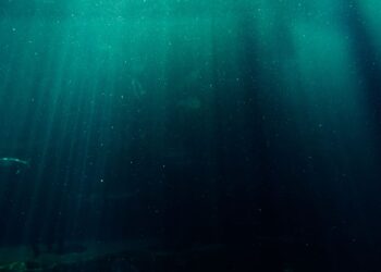 Pemandangan laut dalam yang gelap dengan cahaya menembus air, ilustrasi kisah Nabi Yunus di dalam perut ikan