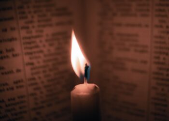 Lilin menyala di samping buku tua yang terbuka, ilustrasi pembahasan Doa Nurbuat