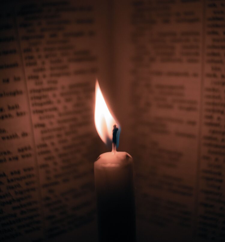 Lilin menyala di samping buku tua yang terbuka, ilustrasi pembahasan Doa Nurbuat
