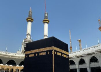 Jamaah haji berpakaian ihram putih menghadap Ka'bah di siang hari, ilustrasi keutamaan haji mabrur