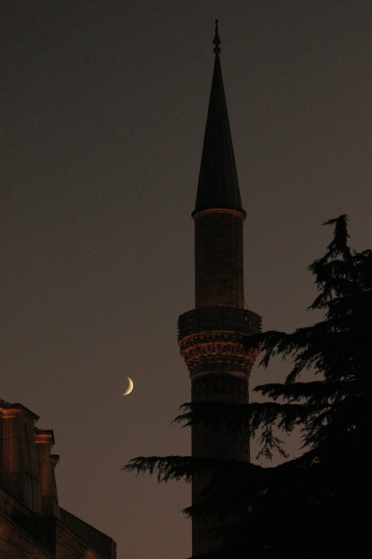 Menara masjid dengan bulan sabit di langit malam, ilustrasi peristiwa Isra Mi'raj Rasulullah shallallahu alaihi wasallam