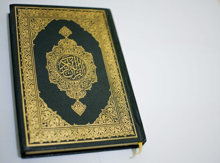Mushaf Al-Qur'an tertutup dengan sampul hijau berhias kaligrafi emas, ilustrasi keutamaan khatam Al-Qur'an
