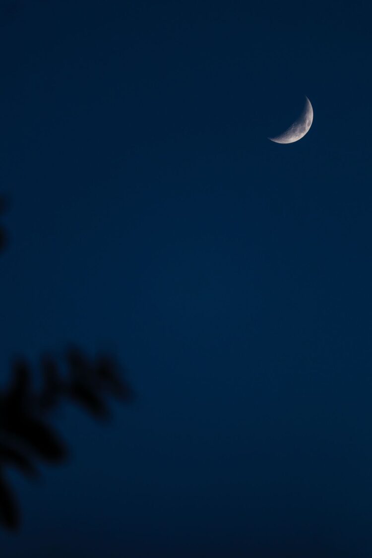 Bulan sabit bersinar di langit malam biru gelap, ilustrasi keutamaan bulan Muharram sebagai bulan Allah