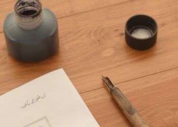 Perlengkapan kaligrafi klasik berupa tinta, pena, dan tulisan tangan di atas meja kayu, ilustrasi pembahasan Sholawat Nariyah