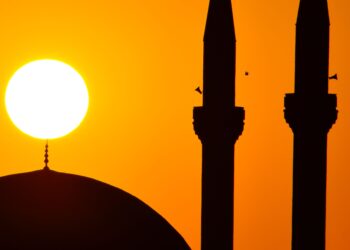 Siluet menara dan kubah masjid saat matahari terbenam, ilustrasi keutamaan kalimat tahlil laa ilaaha illallah