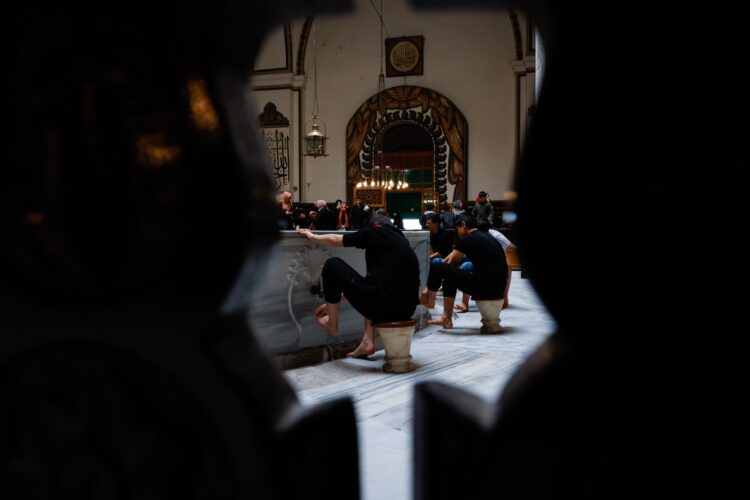 Jamaah berwudhu membasuh kaki di tempat wudhu masjid, ilustrasi keutamaan wudhu sebagai penggugur dosa