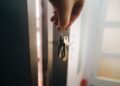 Tangan memegang kunci di depan pintu apartemen, ilustrasi hukum kumpul kebo dalam Islam