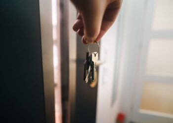 Tangan memegang kunci di depan pintu apartemen, ilustrasi hukum kumpul kebo dalam Islam
