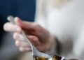 Tangan menuangkan obat batuk sirup ke sendok, ilustrasi hukum obat dan vaksin saat puasa