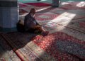 Seorang pria membaca Al-Qur'an di masjid, ilustrasi hukum ruqyah dalam Islam