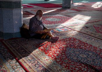 Seorang pria membaca Al-Qur'an di masjid, ilustrasi hukum ruqyah dalam Islam
